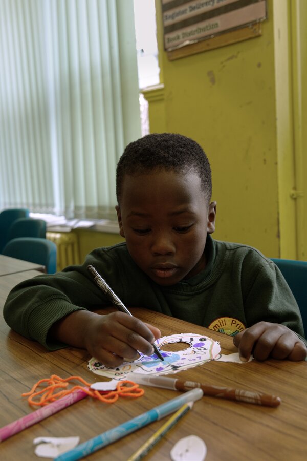 Pupil sat at a desk creating a colourful mask